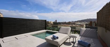 Terraza en la azotea con piscina, dos sillones de relax y una pequeña mesa.