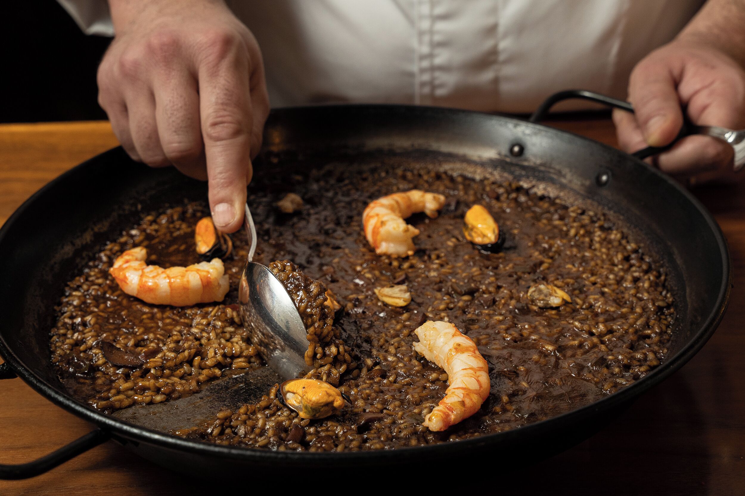 Iemand bereidt een gerecht met garnalen en linzen in een pan.