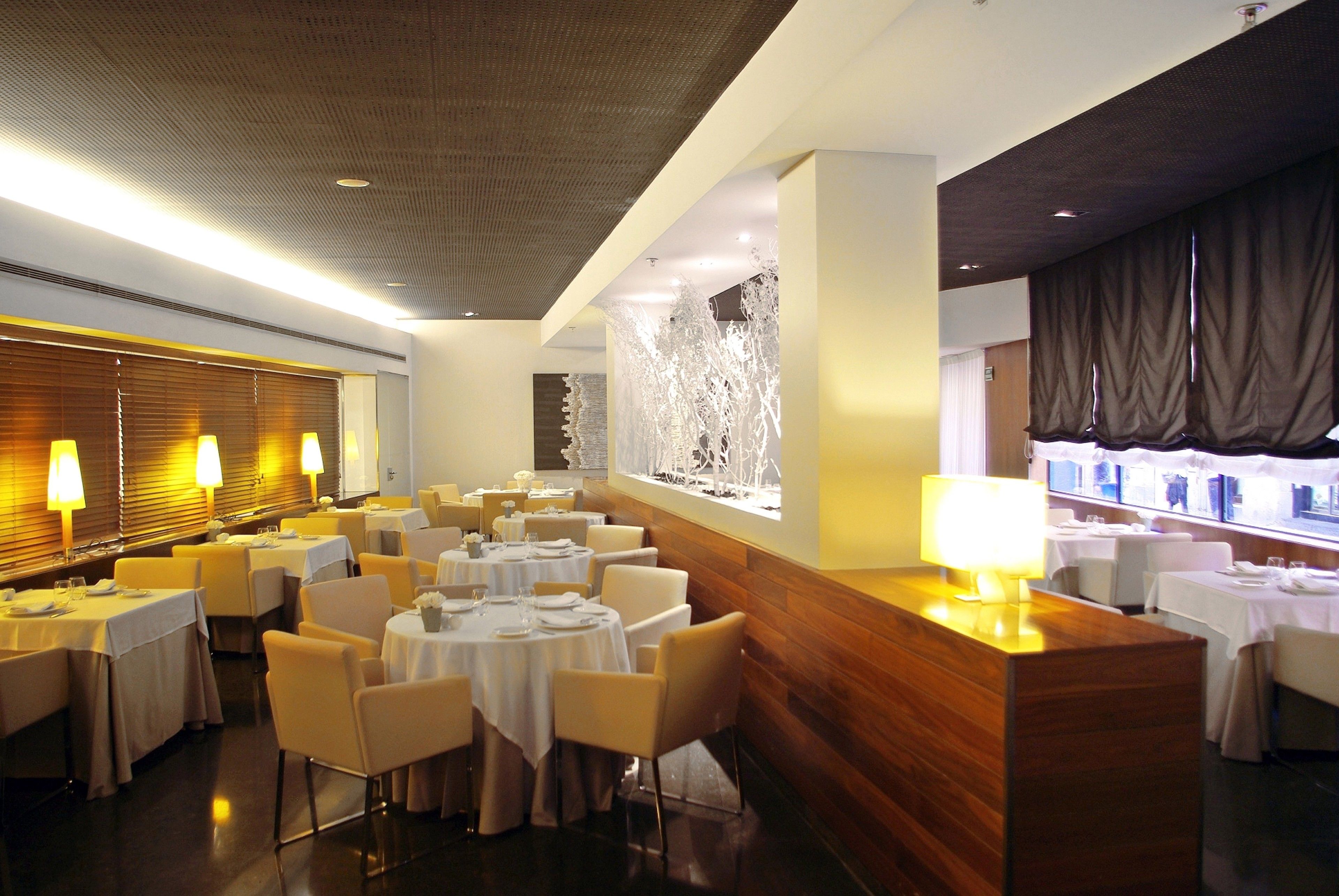 A restaurant with round tables, chairs, and a wooden counter.