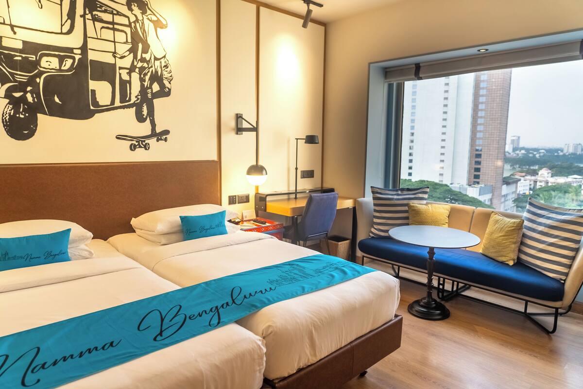 Une chambre d’hôtel avec un lit, un canapé, un bureau et une vue sur la ville.