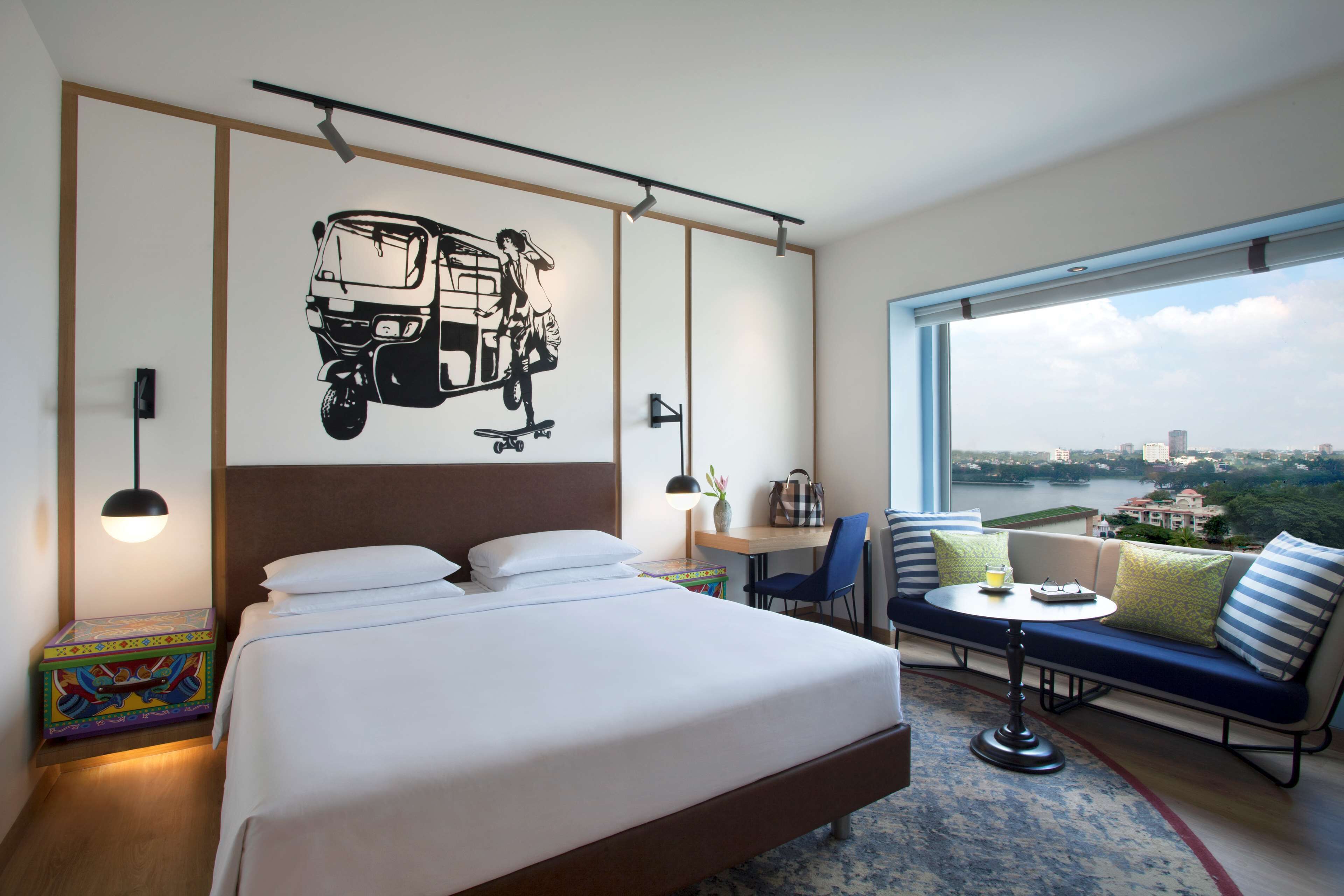 Une chambre d’hôtel avec un grand lit, un bureau, un canapé et une vue sur une rivière et le paysage urbain.