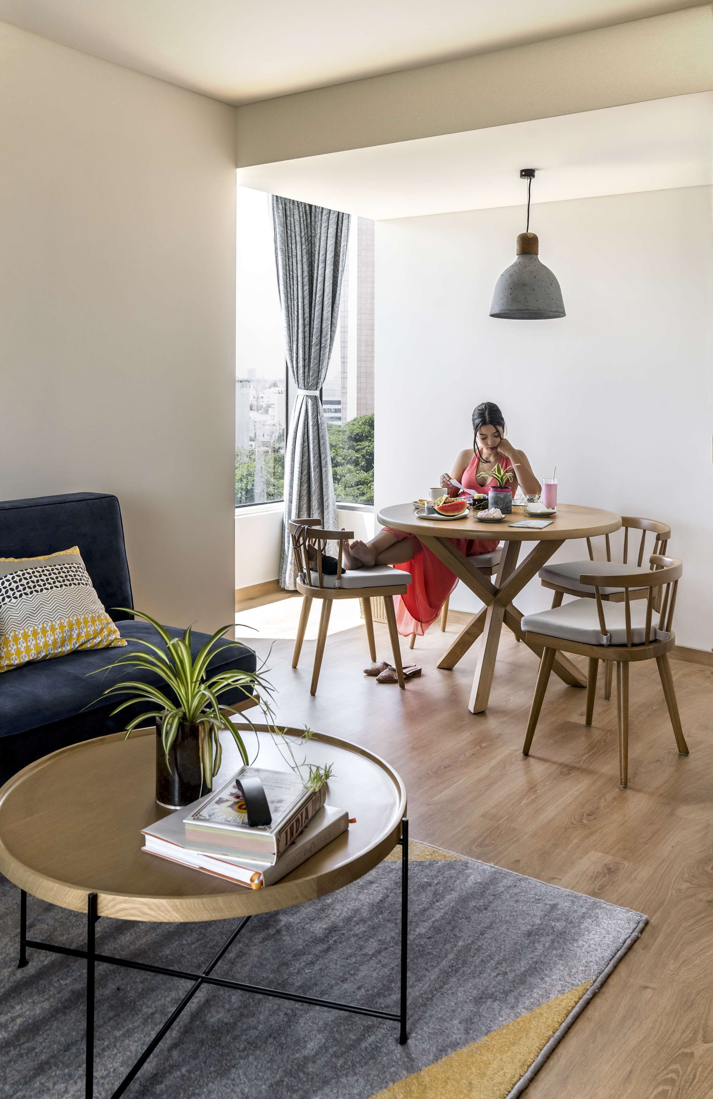 A modern living room with a round coffee table, a sofa, and a dining area with a table and chairs.