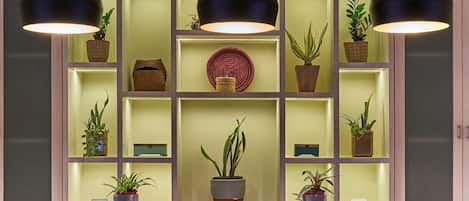 Una cocina moderna con tres taburetes de bar, iluminación colgante y un estante empotrado para plantas.