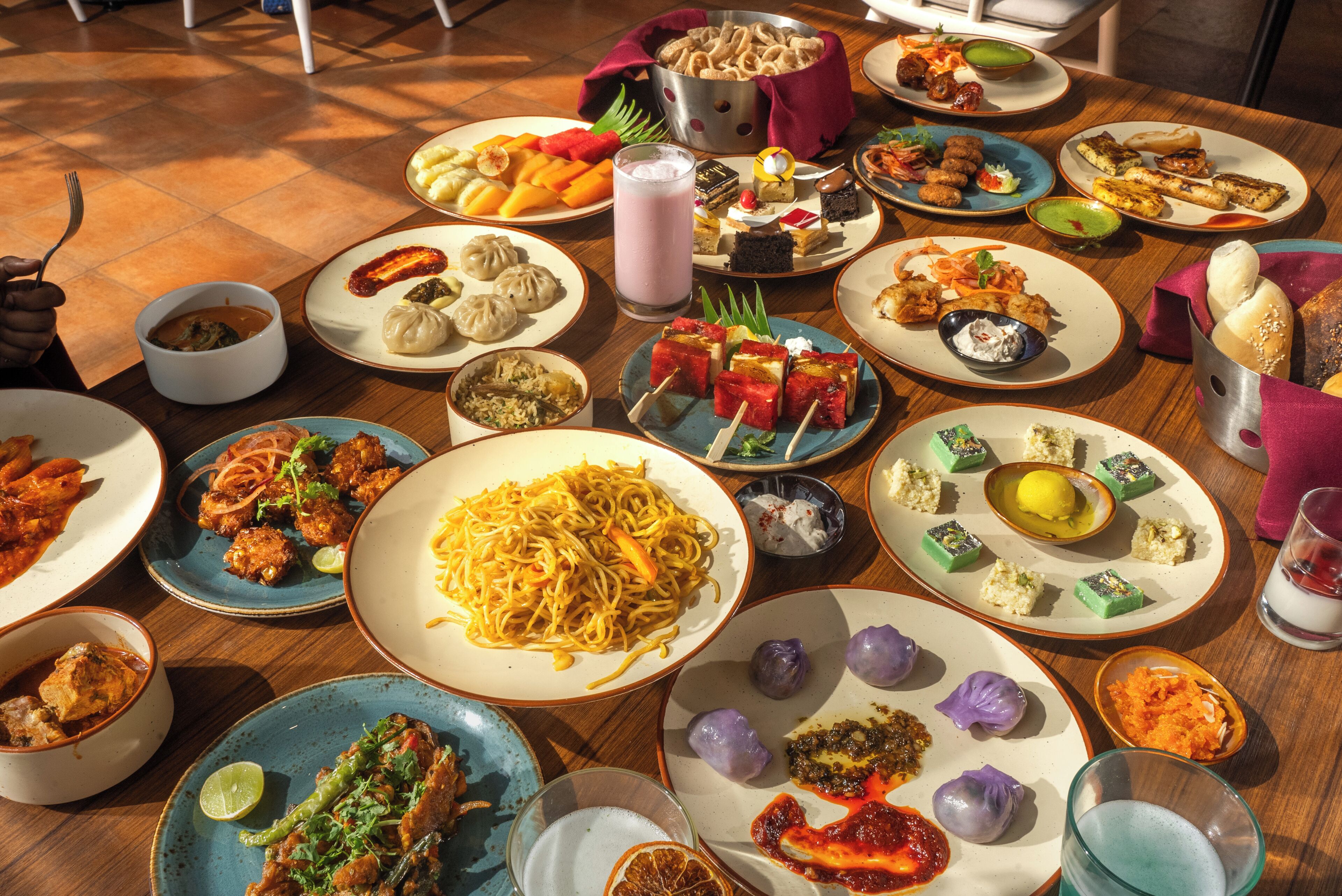A variety of dishes on a table, including noodles, dumplings, and desserts.