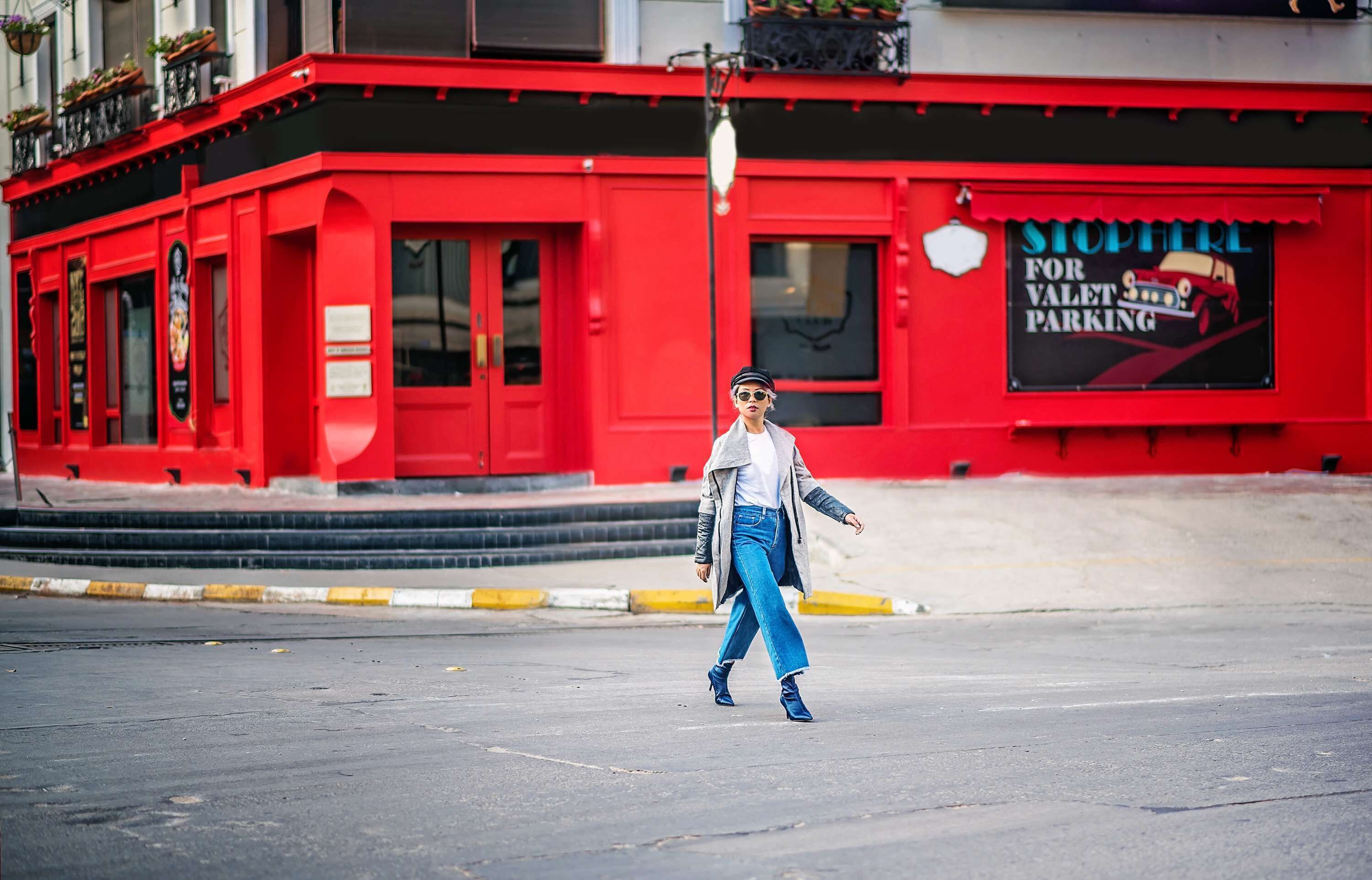 A person walking in front of a red building with a sign for valet parking.