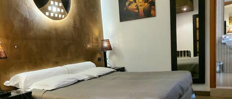 A hotel room with a bed, a nightstand, a lamp, and a painting on the wall.