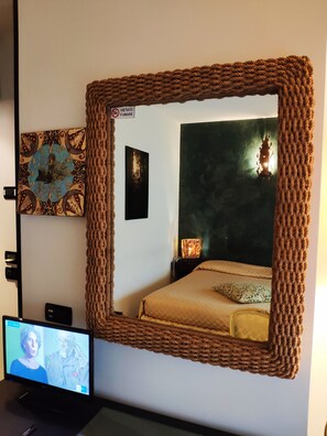 Een slaapkamer met een grote spiegel, een televisie en kunstwerken aan de muur.