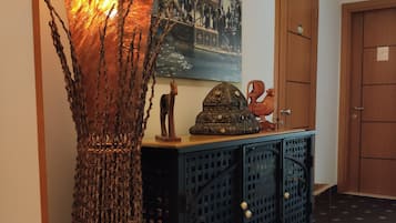 A hallway with a decorative lamp, a cabinet with a patterned top, and a framed picture on the wall.
