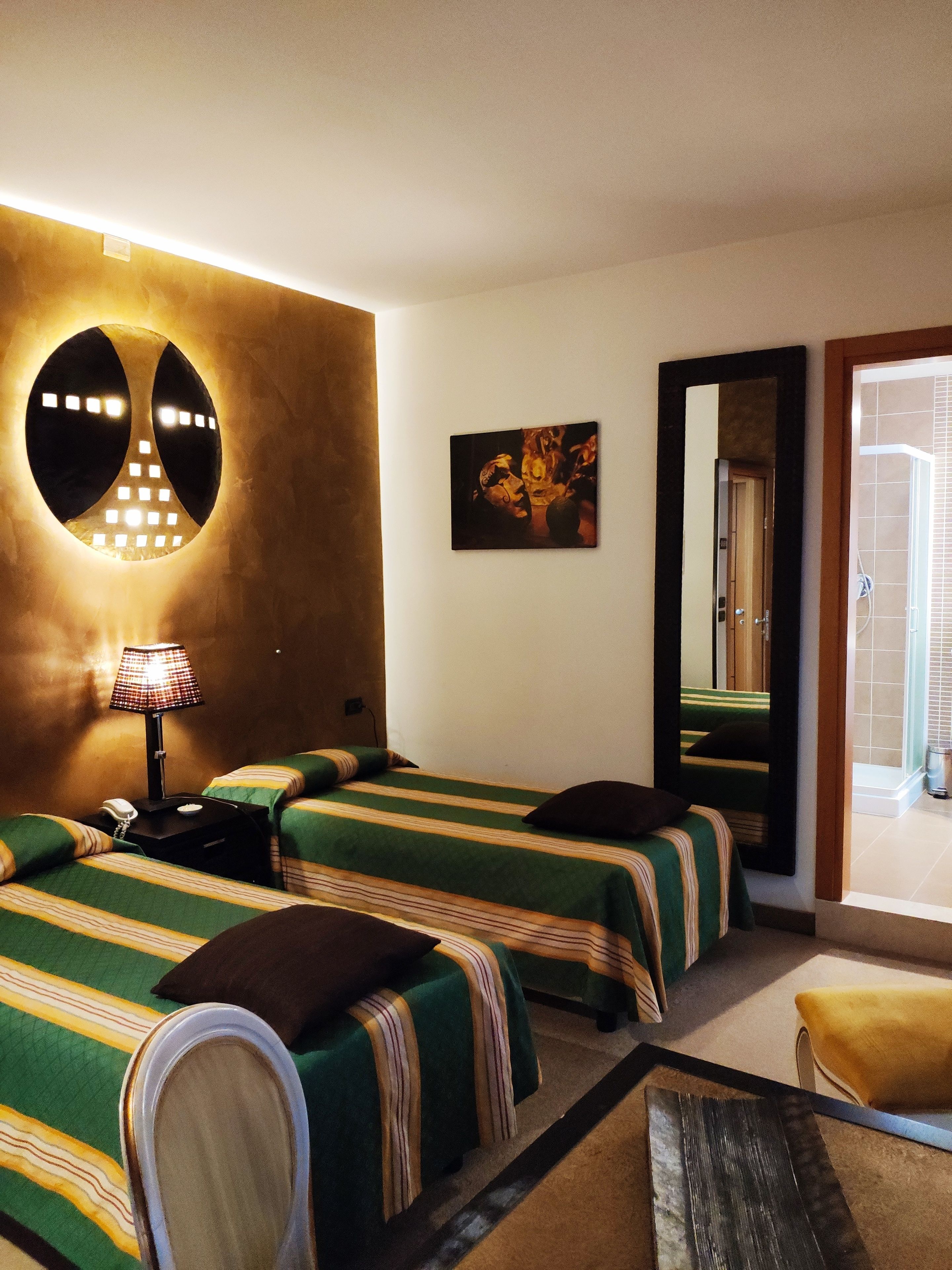 Une chambre d’hôtel avec deux lits, une table de chevet avec une lampe, un miroir et une vue sur l’extérieur.