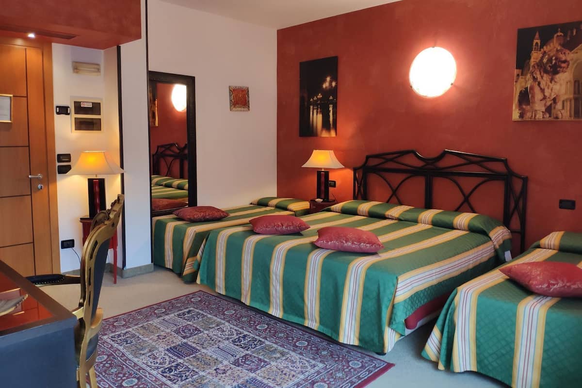 Ein Hotelzimmer mit zwei Betten, einem Schreibtisch, einem Stuhl, einem Spiegel, einer Lampe und einem Teppich.