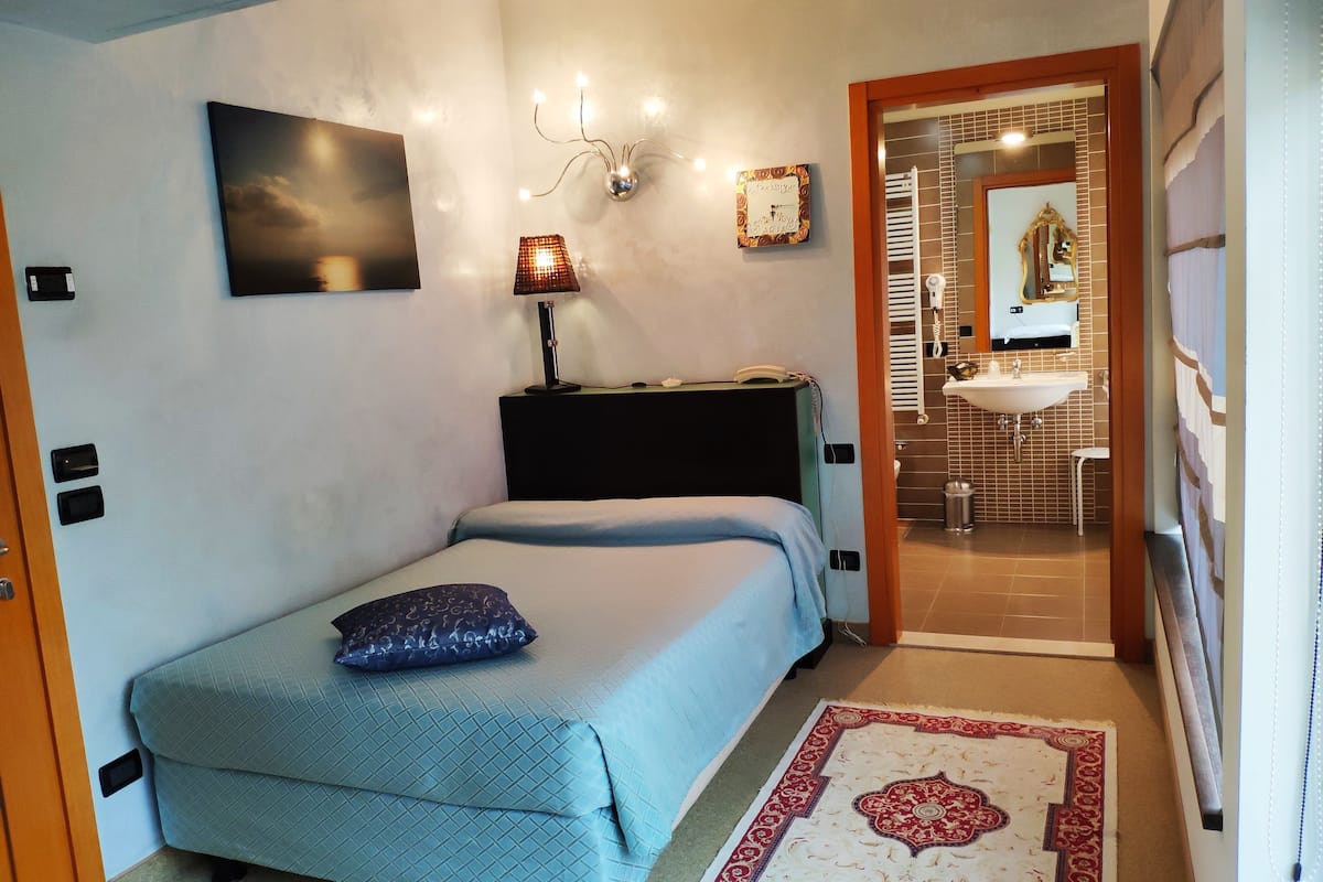Ein Schlafzimmer mit Bett, Nachttischlampe und einem Bild an der Wand.