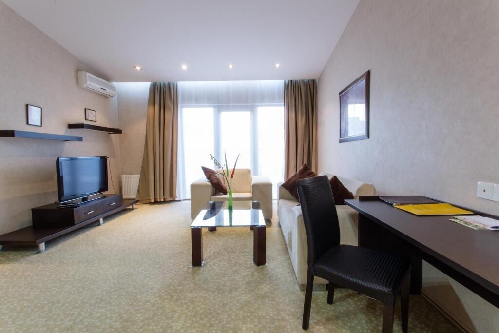 Une chambre d’hôtel équipée d’une télévision, d’un canapé, d’une table à manger et d’une chaise.
