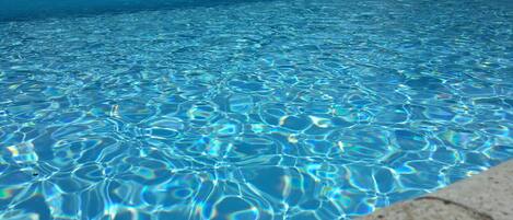 Una piscina al aire libre de temporada, sombrillas