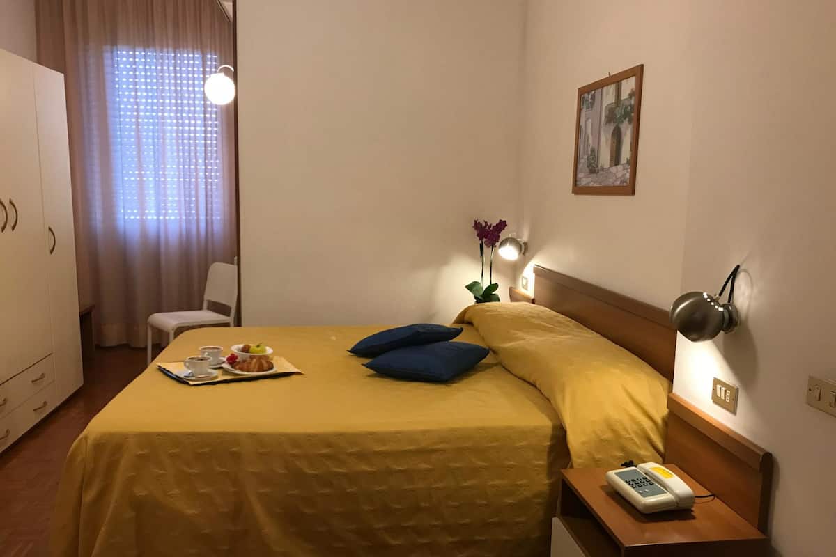 Une chambre d’hôtel avec un lit, une table de chevet, une lampe et un tableau au mur.