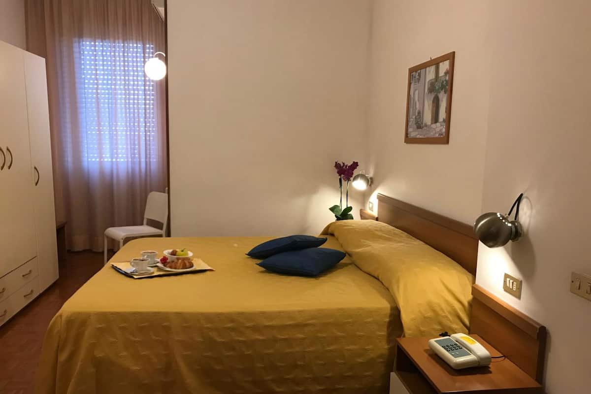 Une chambre d’hôtel avec un lit, une table de chevet, une lampe et un tableau au mur.