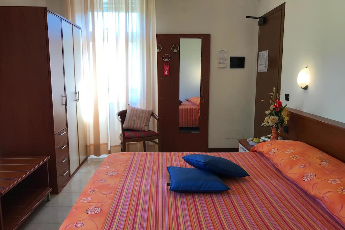 Une chambre d’hôtel avec un lit, une chaise, une armoire et un bureau.