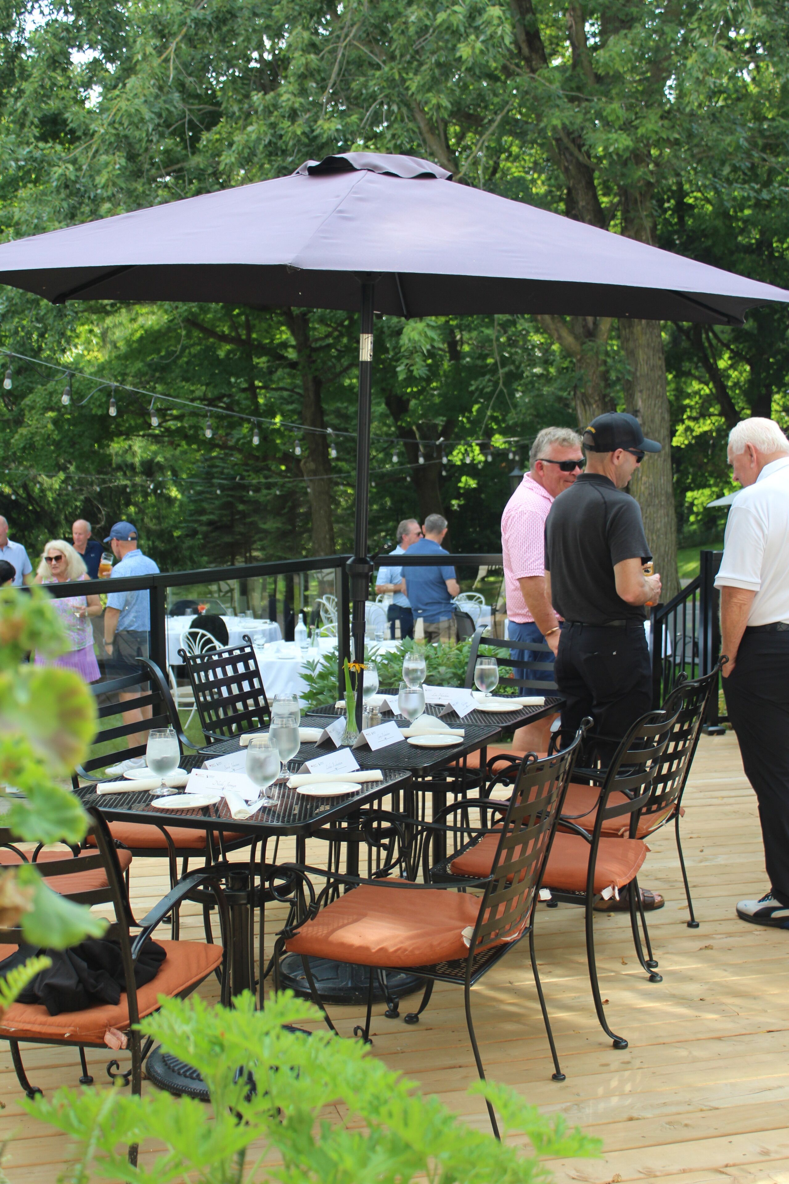 Un espace extérieur aménagé pour les repas, avec des tables et des chaises, entouré d’arbres.