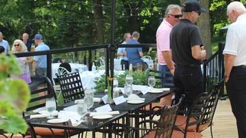 Un espace extérieur aménagé pour les repas, avec des tables et des chaises, entouré d’arbres.