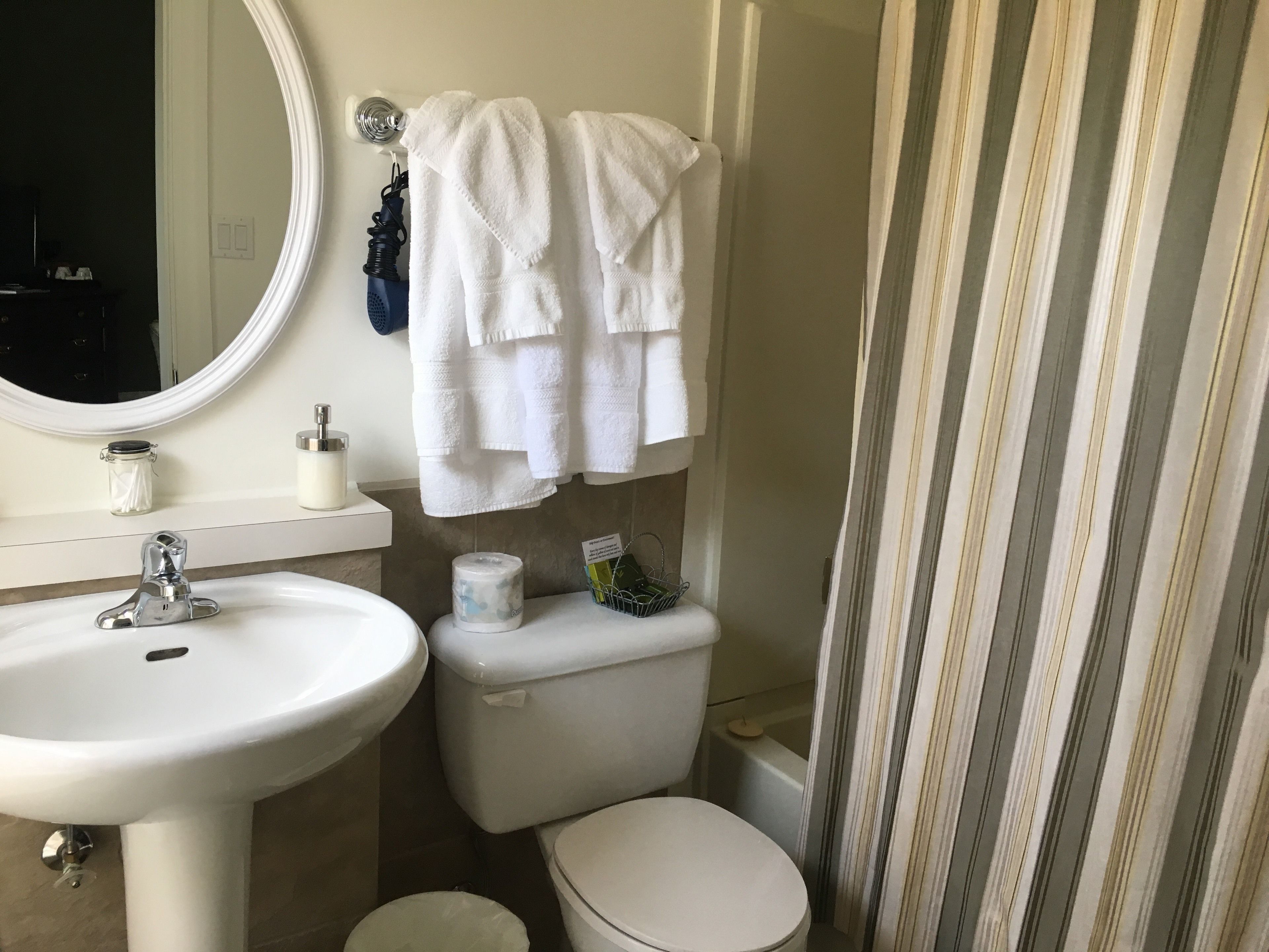 A bathroom with a white sink, a mirror, a toilet, and a shower curtain.