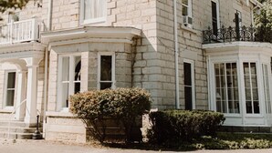 Un edificio histórico de piedra con un ventanal saliente y un balcón decorativo.