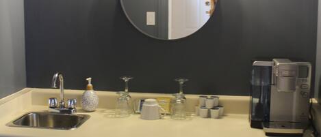 Un baño moderno con lavabo, espejo y cafetera.
