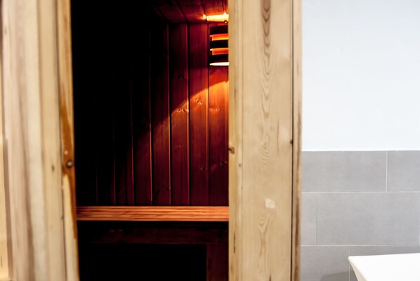 Una sauna de madera con un banco, un revestimiento de azulejos y un marco de puerta de madera.
