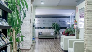 Un área de recepción con un sofá, sillas y una planta.