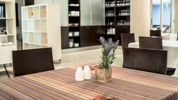 A dining area with striped tablecloths, a potted plant, salt and pepper shakers, and a fork and knife on the table.