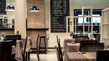 A restaurant with tables covered in striped tablecloths, a menu on the wall, and pendant lighting.
