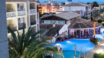 A resort with a swimming pool, multiple balconies, and a covered outdoor area.