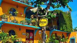 A vibrant hotel with a yellow facade, a balcony with plants, and a sign reading "CAROONN HOTEL". - Cabo Inn Hotel (Cabo San Lucas)