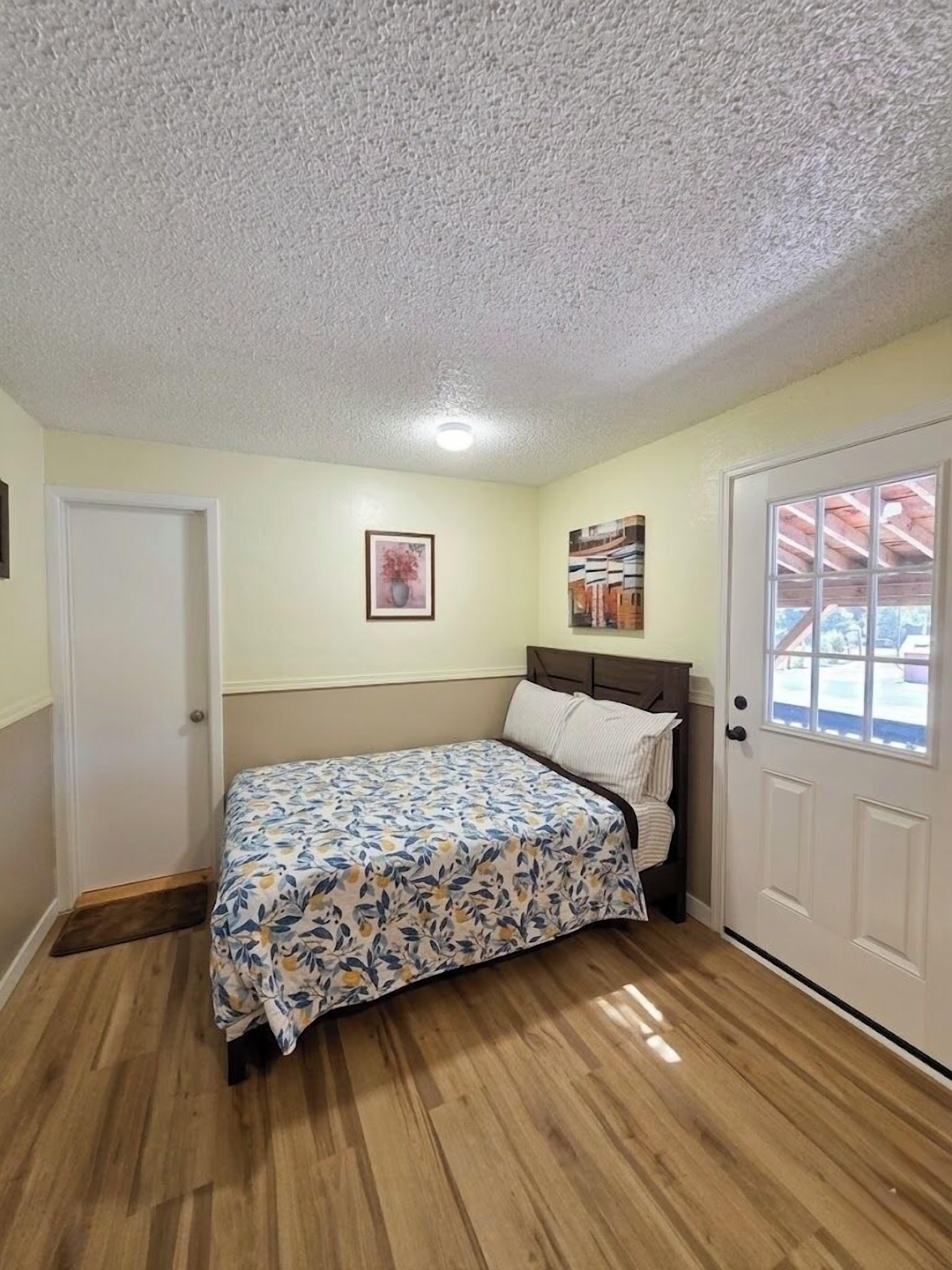 A bedroom with a bed, a door, and a window.