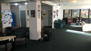 Um espaço amplo e interno, com área de estar, cozinha compacta e estante de livros.