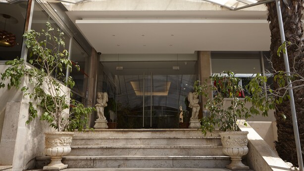 A set of stone steps leading to a modern building entrance with glass doors and two large potted plants on either side. - Zoukotel Hotel (Jounieh)