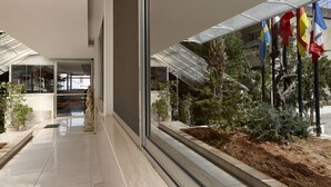 A modern building with a glass entrance, potted plants, and flags. - Zoukotel Hotel (Jounieh)