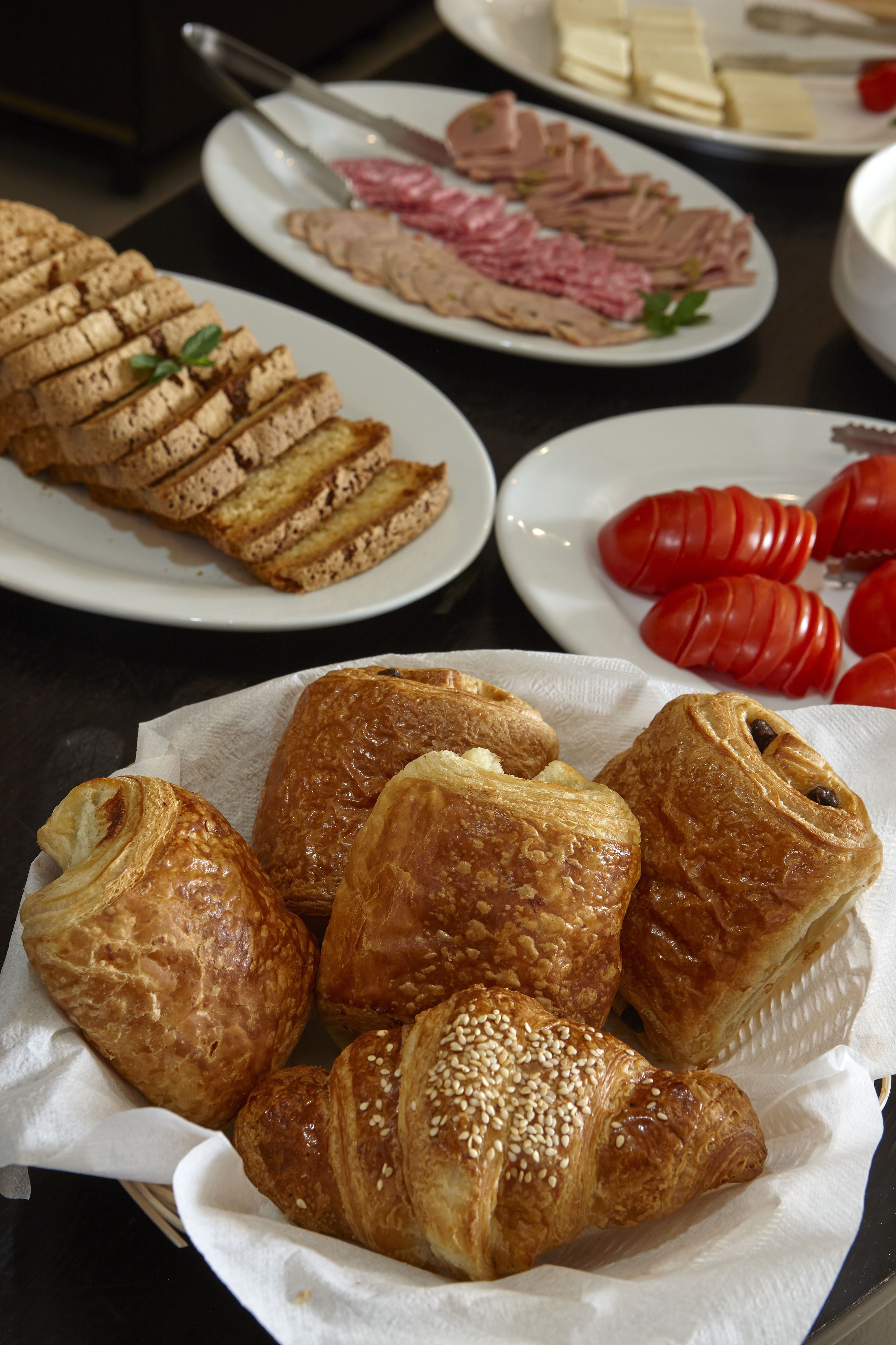 A table with various food items including croissants and sliced meats.