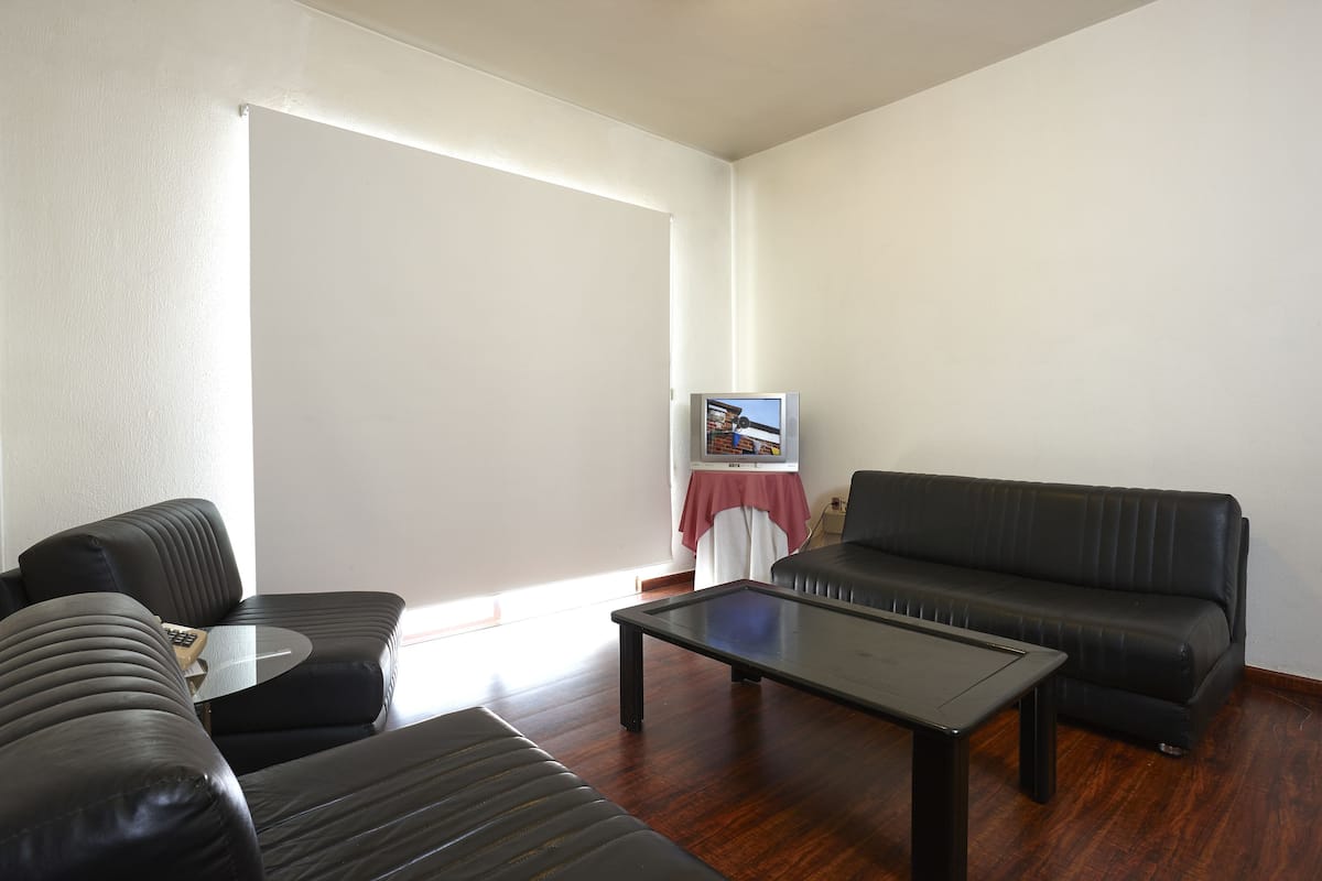 Una sala de estar con sofá, mesa de centro y televisor sobre un mueble.