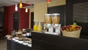A buffet setup with various food items and beverages, including fruits and juices, in a modern setting with pendant lighting. - Zoukotel Hotel (Jounieh)