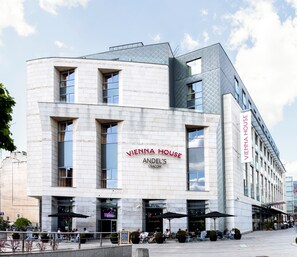 Vienna House, a modern building with a prominent sign, large windows, and outdoor seating area. - Vienna House by Wyndham Andel's Cracow (Kraków)