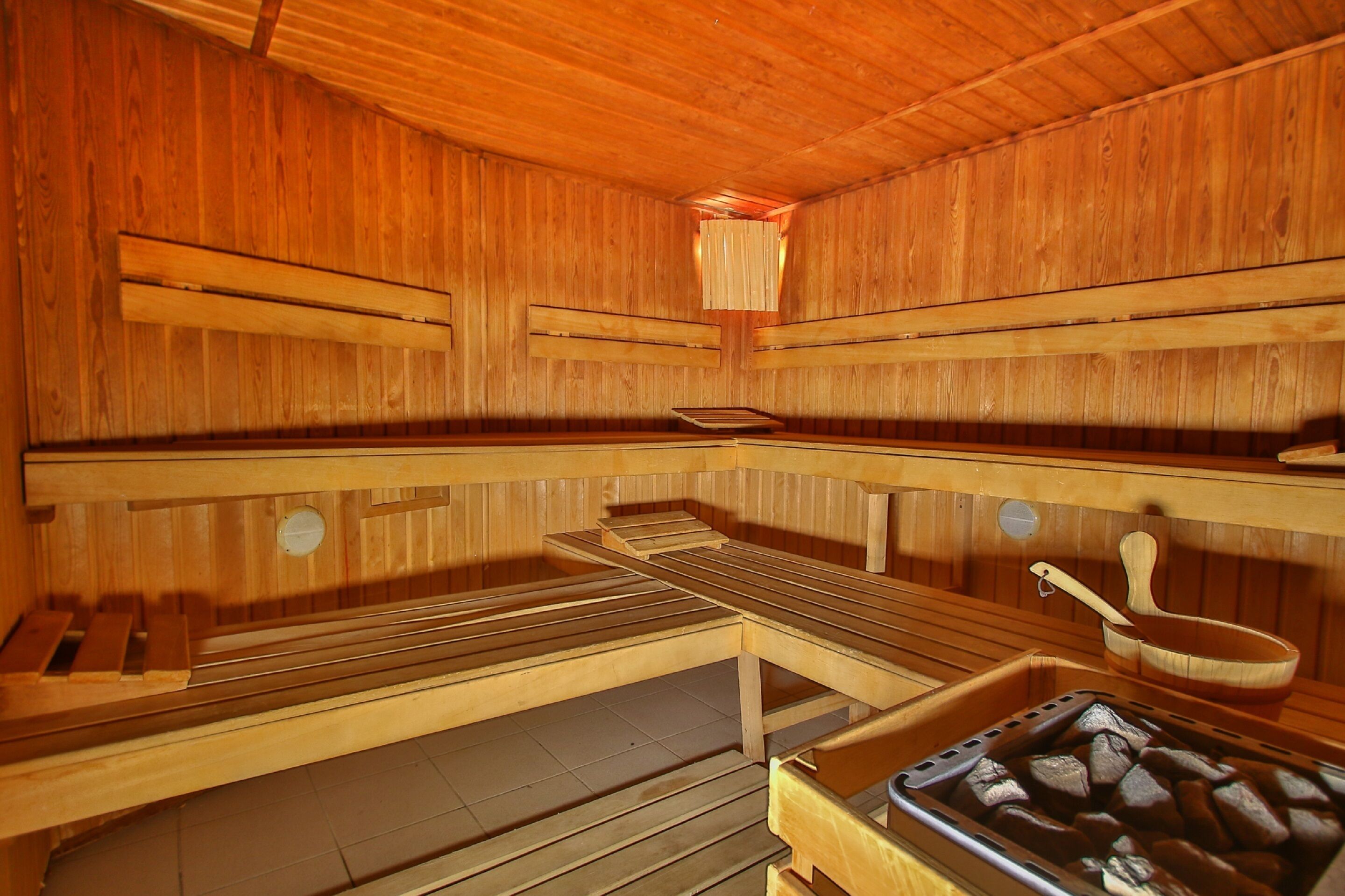 Una sauna de madera con bancos y un balde de madera.