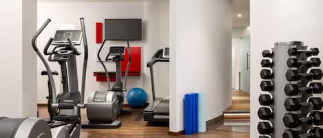 Un gimnasio moderno con diversos equipos de ejercicio, incluyendo cintas de correr, elípticas y una bicicleta estática.