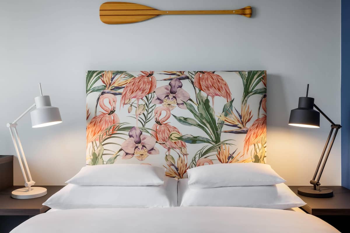 A neatly made bed with white pillows and two bedside lamps on either side.