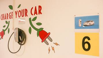 A wall with a charging station and a sign that says "CHARGE YOUR CAR".