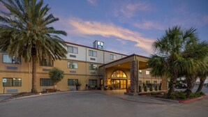 A hotel with a large entrance, palm trees, and a clear sky. - Best Western San Isidro Inn (Laredo)