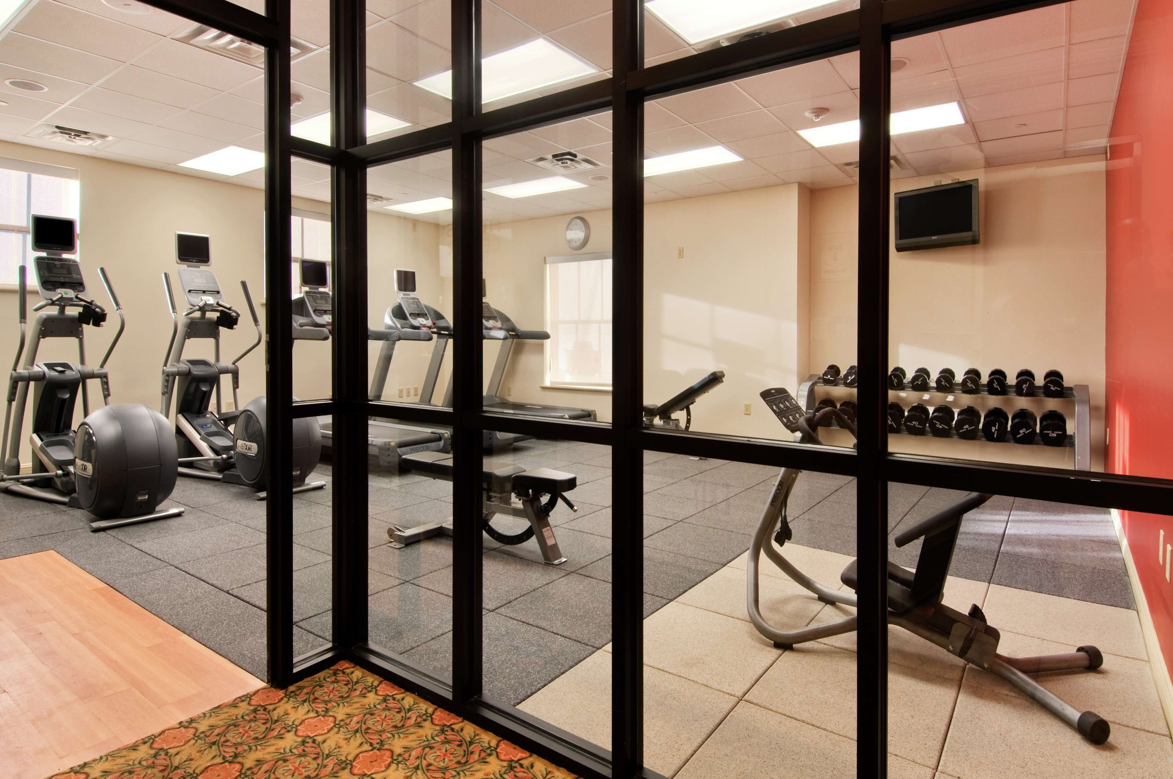 A gym with various exercise equipment, including treadmills, elliptical machines, and free weights.