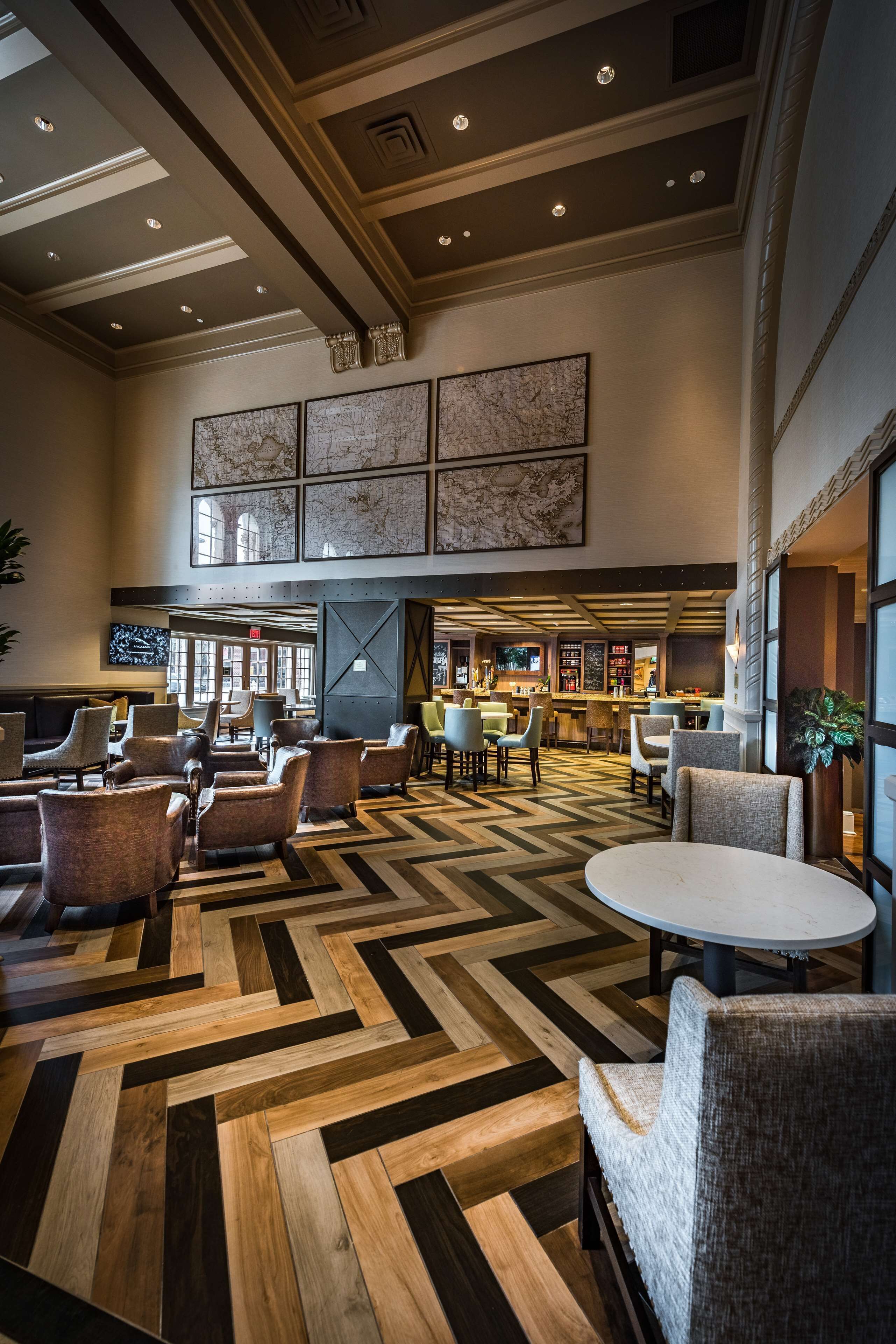 Un vestíbulo amplio con suelo de diseño espiga, varias zonas de estar y un área de bar/lounge.