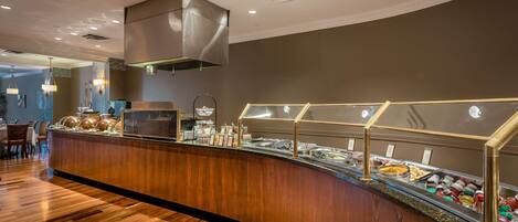 A buffet area with a curved wooden counter, glass display cases, and overhead lighting.