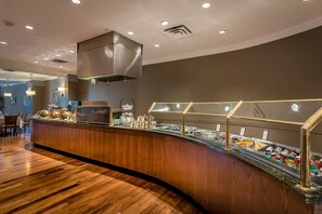 A buffet area with a curved wooden counter, glass display cases, and overhead lighting.