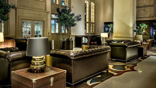A spacious lobby with leather sofas, a large chandelier, and a grand staircase. - Hilton Baton Rouge Capitol Center (Baton Rouge)