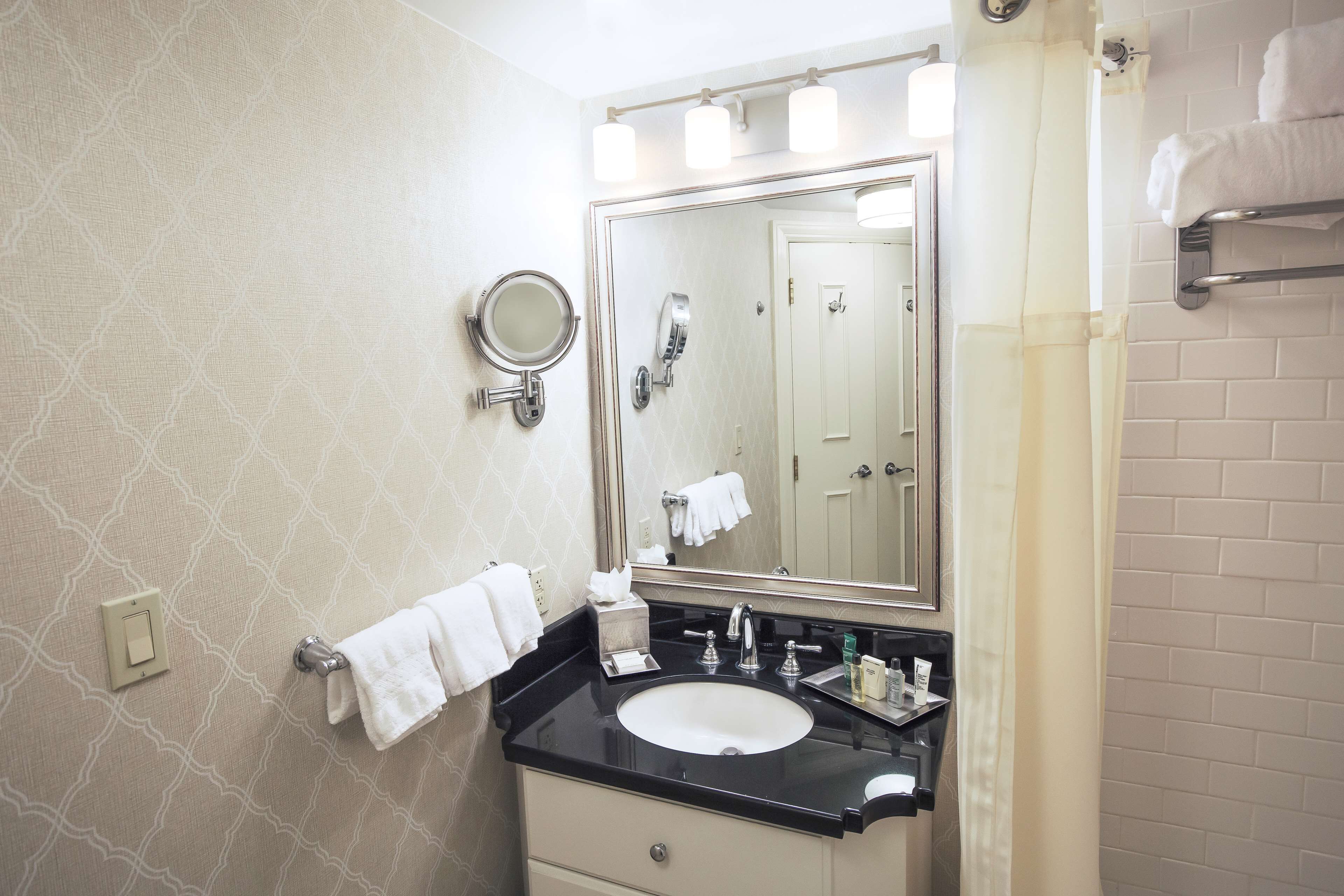A bathroom with a sink, mirror, towel rack, and a shower curtain.